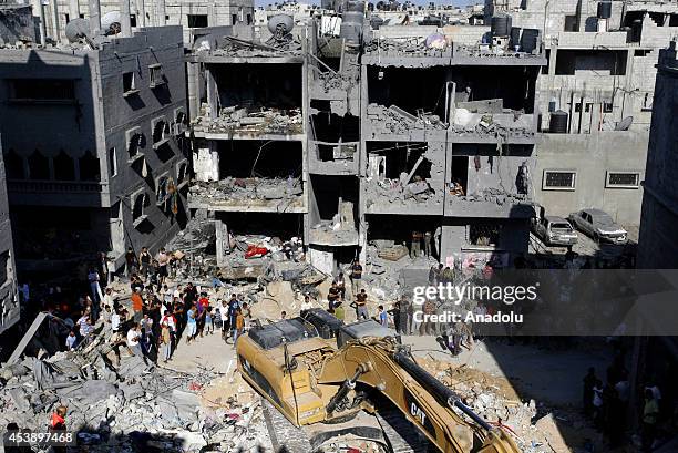 Search and rescue team members accompanied Palestinian local residents inspect the rubble of a destroyed house, after it was hit by an Israeli...