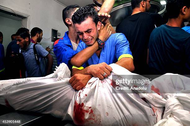 Palestinian man mourns over the body of Palestinian who were killed in an Israeli air strike targeting the Sheik Radwan cemetery, in the morgue of...