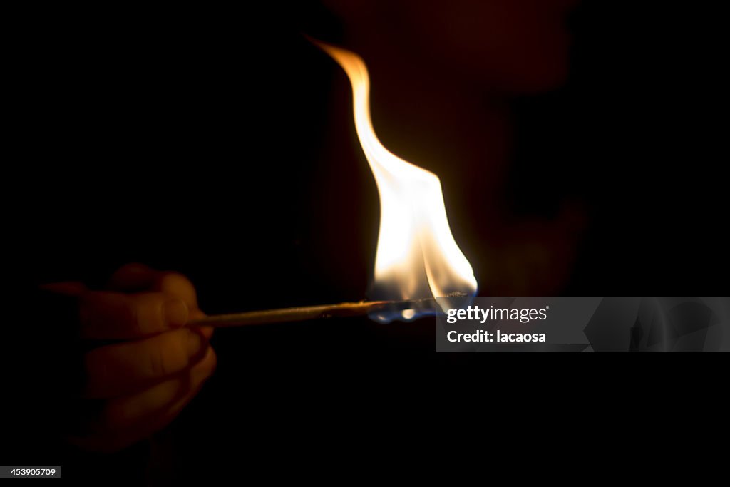 Hand with burning matchstick