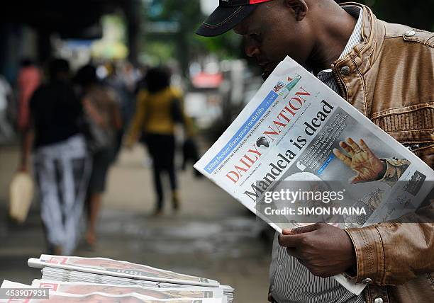 Man buys a newspaper with headline on the death of former South African president Nelson Mandela on December 6, 2013 in Nairobi. Mandela, the revered...