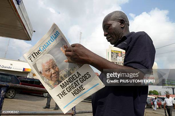 Man reads A newspaper with headline on the death of former South African president Nelson Mandela on December 6, 2013 in Lagos. Mandela, the revered...
