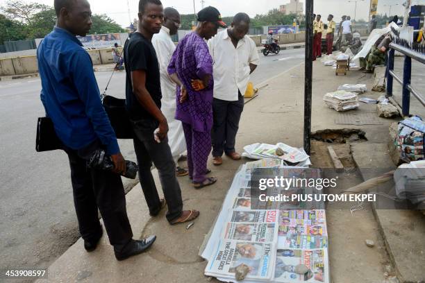 Men stand by newspapers with headlines on the death of former South African president Nelson Mandela on December 6, 2013 in a street of Lagos....