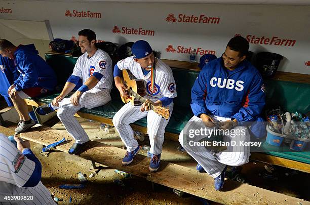 John Baker of the Chicago Cubs sits on the bench with teammates Chris Valaika and Hector Rondon as they wait out an over 4 hour delay after heavy...