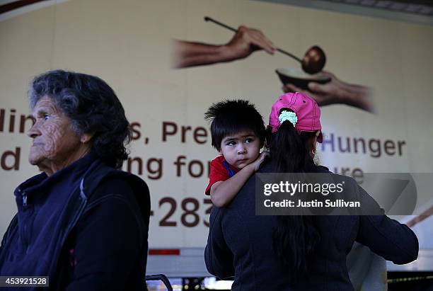 Young boy waits in line with his mother as during a Community Food Bank food giveaway the needy on August 21, 2014 in Firebaugh, California. As the...