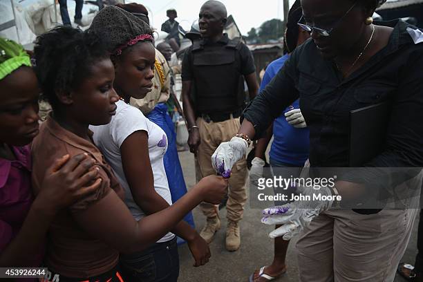 Residents of the West Point slum are marked with ink just before receiving food aid during the second day of the government's Ebola quarantine on...