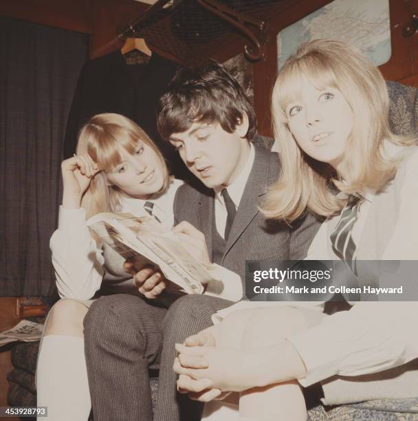 Paul McCartney completes a crossword puzzle with Patti Boyd and another extra on a train from Marylebone Station during the filming of 'A Hard Day's...