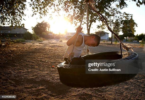 Young boy plays on a tire swing on August 21, 2014 in Mendota, California. As the severe California drought continues for a third straight year,...