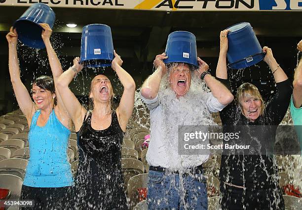 Participants tip buckets of ice water over their heads as they take part in the World Record Ice Bucket Challenge at Etihad Stadium on August 22,...