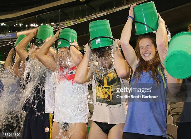 Participants tip buckets of ice water over their heads as they take part in the World Record Ice Bucket Challenge at Etihad Stadium on August 22,...