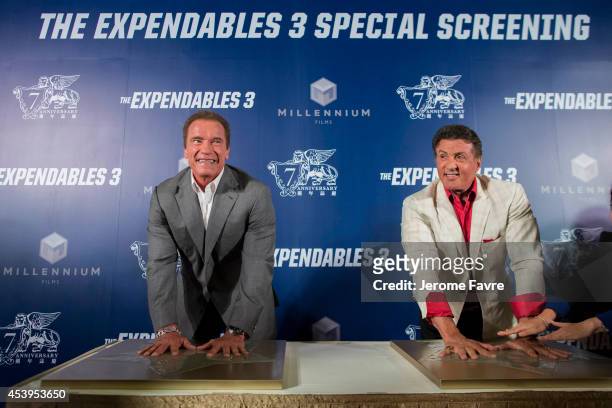 Sylvester Stallone, right, and Arnold Schwarzenegger show off their hand prints during a photocall at a special screening of "The Expendables 3" at...