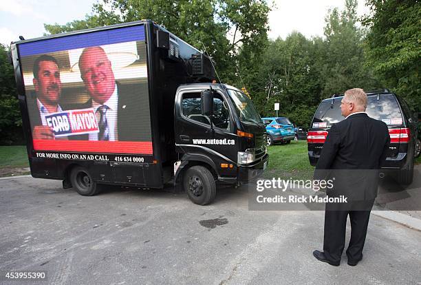 Doug Ford watchers as a screen truck showing a Rob Ford video repositions next the Diane Ford's house. Rob Ford fundraiser was held at his mother...