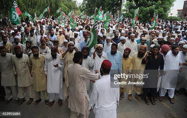 Activists of Pakistani religious party Ahle Sunnat Wal Jamaat hold their flags as they march during an anti Imran Khan and Tahir-ul-Qadri protest...