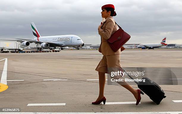 An Emirates air stewardess pulls a luggage case as she walks across the tarmac near one of the airline's Airbus A380 aircraft at Terminal 3 of...