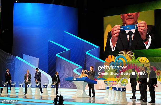 Secretary General Jerome Valcke holds up the name of USA during the Final Draw for the 2014 FIFA World Cup Brazil at Costa do Sauipe Resort on...