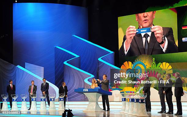 Secretary General Jerome Valcke holds up the name of Uruguay during the Final Draw for the 2014 FIFA World Cup Brazil at Costa do Sauipe Resort on...