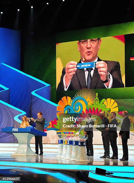 Secretary General Jerome Valcke holds up the name of Switzerland during the Final Draw for the 2014 FIFA World Cup Brazil at Costa do Sauipe Resort...