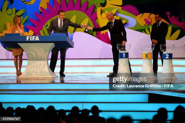 Zinedine Zidane passes one of the draw balls to FIFA Secretary General Jerome Valcke during the Final Draw for the 2014 FIFA World Cup Brazil at...