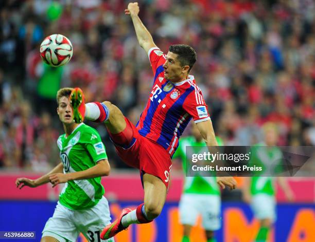 Robert Lewandowski of Muenchen challenges Robin Knoche of Wolfsburg during the Bundesliga match between FC Bayern Muenchen and VfL Wolfsburg at...