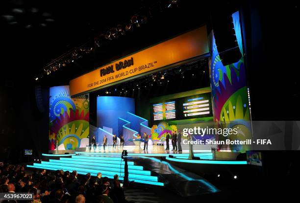 The draw assistants wait behind the pots as Fernanda Lima and FIFA Secretary General Jerome Valcke talk to the audience during the Final Draw for the...