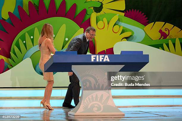 Secretary General Jerome Valcke collects one of the draw balls after was dropped on the floor next to host Fernanda Lima during the Final Draw for...