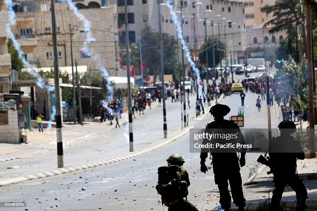 Israeli soldiers look on as tear gas canisters rain down on...