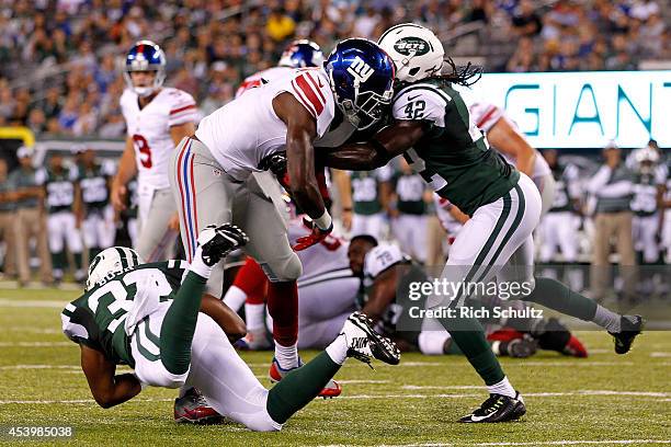 Corey Washington of the New York Giants is tackled by Josh Bush and Brandon Dixon of the New York Jets during a preseason the fourth quarter of a...