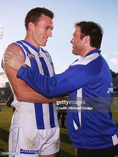 Drew Petrie of the Kangaroos and coach Brad Scott celebrate the win during the round 22 AFL match between the North Melbourne Kangaroos and the...