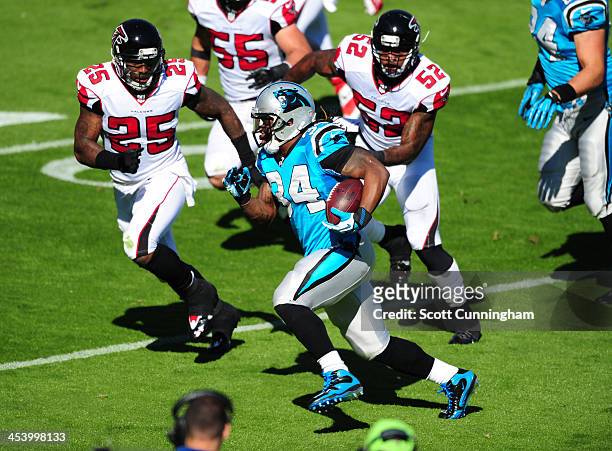 DeAngelo Williams of the Carolina Panthers carries the ball against Akeem Dent and William Moore of the Atlanta Falcons at Bank of America Stadium on...
