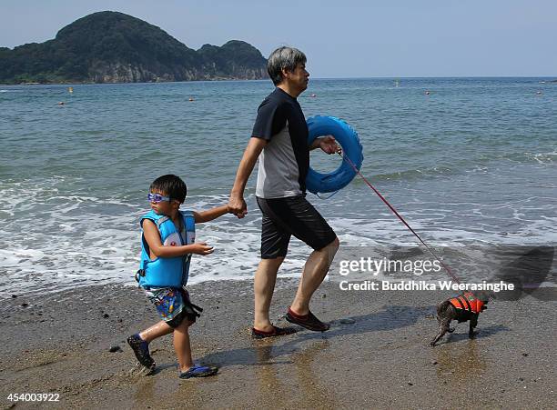 Man walks with his son and pet dog take a bath in the sea at Takeno Beach on August 23, 2014 in Toyooka, Japan. This beach is open for dogs and their...