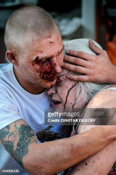 Wounded man hugs an elderly woman after a shelling in the main separatist stronghold in Donetsk on August 23, 2014. Three civilians were killed...