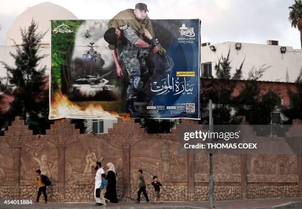 Palestinian family walks past a poster advertising a Palestinian television series based on the kidnapping of Gilad Shalit, an Israeli soldier who...