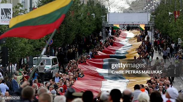 Lithuanians carry a 1000 metre long Lithuanian flag as they march during a celebration of the 25th anniversary of the Baltic Way in Vilnius on August...