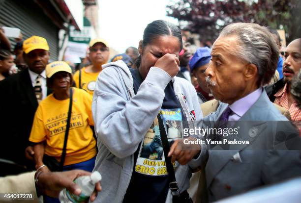 Reverend Al Sharpton comforts Esaw Garner, wife of police violence victim Eric Garner, at his memorial before a rally against police violence on...
