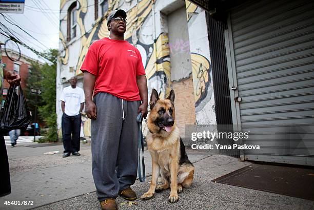 Jerome Jacobs and his German Shepherd dog, King, watch a rally against police violence on August 23, 2014 in the Staten Island borough of New York...