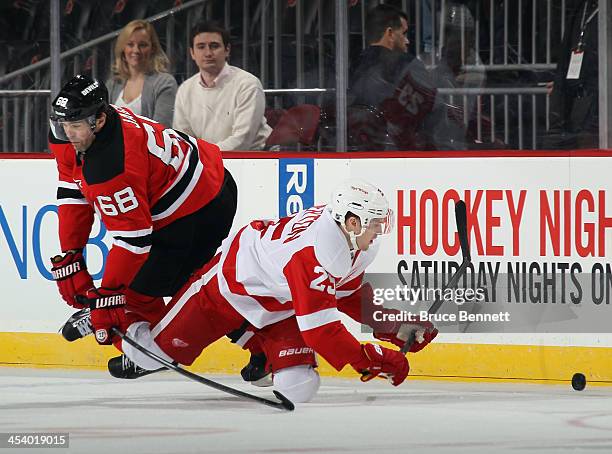 Cory Emmerton of the Detroit Red Wings is tripped up by Jaromir Jagr of the New Jersey Devils during the first period at the Prudential Center on...