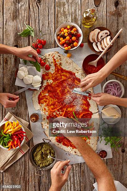 people making a flatbread pizza - pizza ingredients stock pictures, royalty-free photos & images