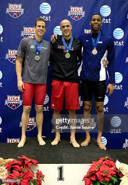 Joao De Lucca stands on the podium alongside second Darian Townsend and third Dax Hill after winning the Men's 200 Yard Freestyle finals during the...