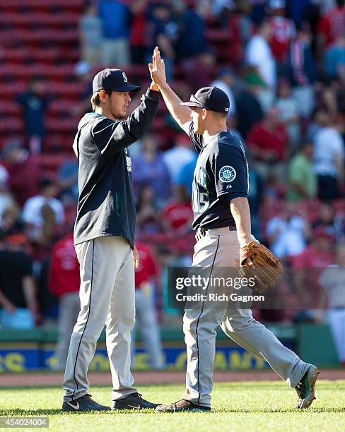 Hisashi Iwakuma of the Seattle Mariners celebrates a 7-3 victory with teammate Kyle Seager against the Boston Red Sox at Fenway Park on August 23,...