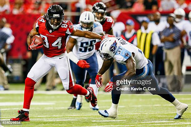 Roddy White of the Atlanta Falcons stiff arms Bernard Pollard of the Tennessee Titans after a catch in the first half of a preseason game at the...