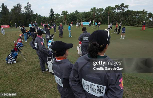 Caddies wait at the side of the practice putting green, ahead of the tournament, on day Two of the Swinging Skirts 2013 World Ladies Masters at...