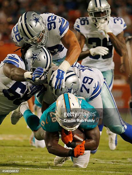 Knowshon Moreno of the Miami Dolphins is brought down by a host of Dallas Cowboys defenders including Stephen Goodin in the second quarter during a...