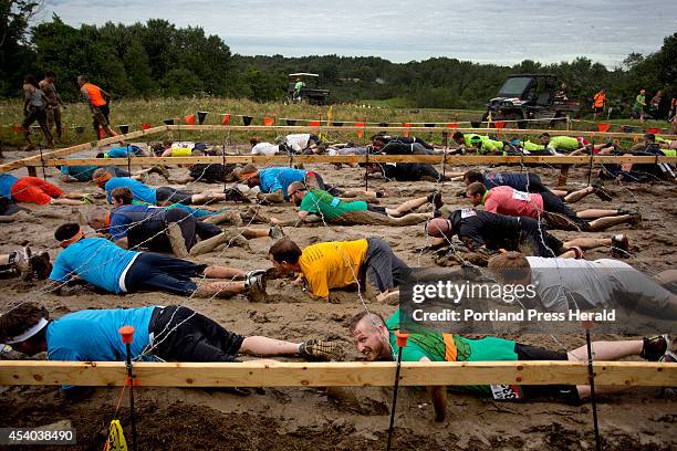 Participants in the Tough Mudder obstacle course, a 10.3 mile trail run littered with obstacles and hazards, compete in the "Kiss the Mud" challenge...