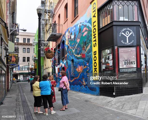 Walking tour guide talks to a small group of tourists in Jack Kerouac Alley which runs between two San Francisco landmarks, City Lights Bookstore and...