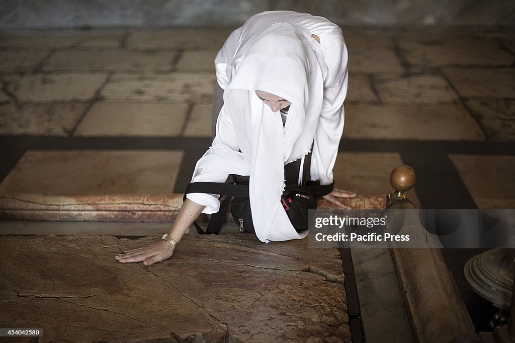 A devotee touches with her hand the Stone of the Anointing...