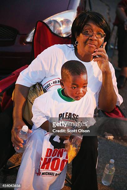 Zellner McCalister and her great-grandson Jordan watch as a parade of demonstrators protesting the shooting death of Michael Brown pass along West...