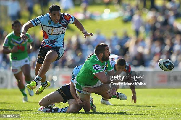 Paul Vaughan of the Raiders gets a pass away as he is tackled during the round 24 NRL match between the Cronulla Sharks and the Canberra Raiders at...