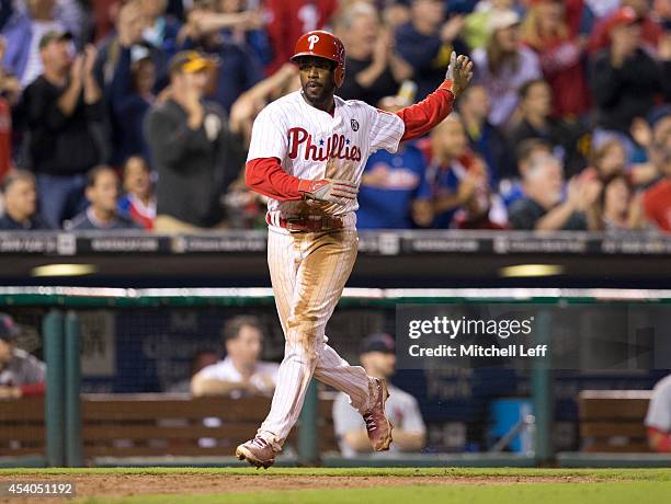 Shortstop Jimmy Rollins of the Philadelphia Phillies waves home second baseman Chase Utley after right fielder Marlon Byrd hit a single in the bottom...