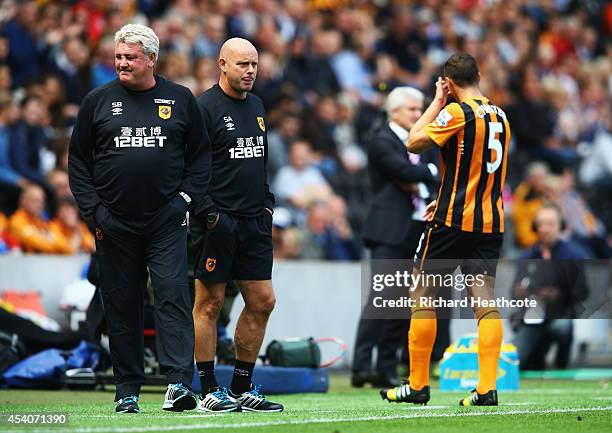 Steve Agnew assistant manager of Hull City looks on as Steve Bruce manager of Hull City reacts as James Chester of Hull City is sent off during the...