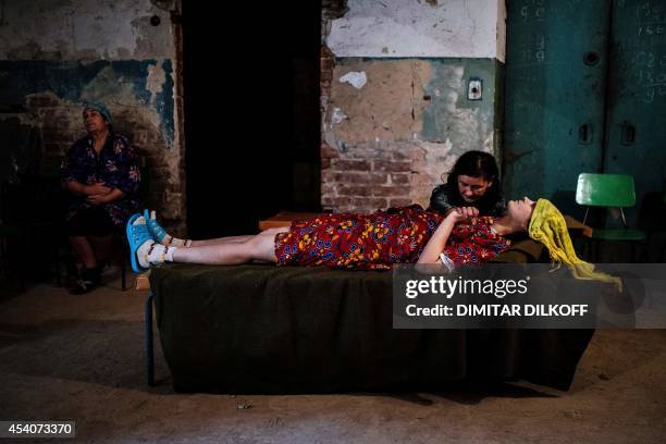 Woman holds the hand of her sick friend in the basement of Kalinina hospital after shelling on August 24, 2014 in Donetsk, eastern Ukraine....