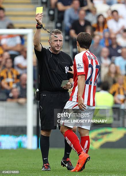 Stoke City's Spanish striker Bojan Krkic receives a yellow card from referee Jon Moss during the English Premier League football match between Hull...